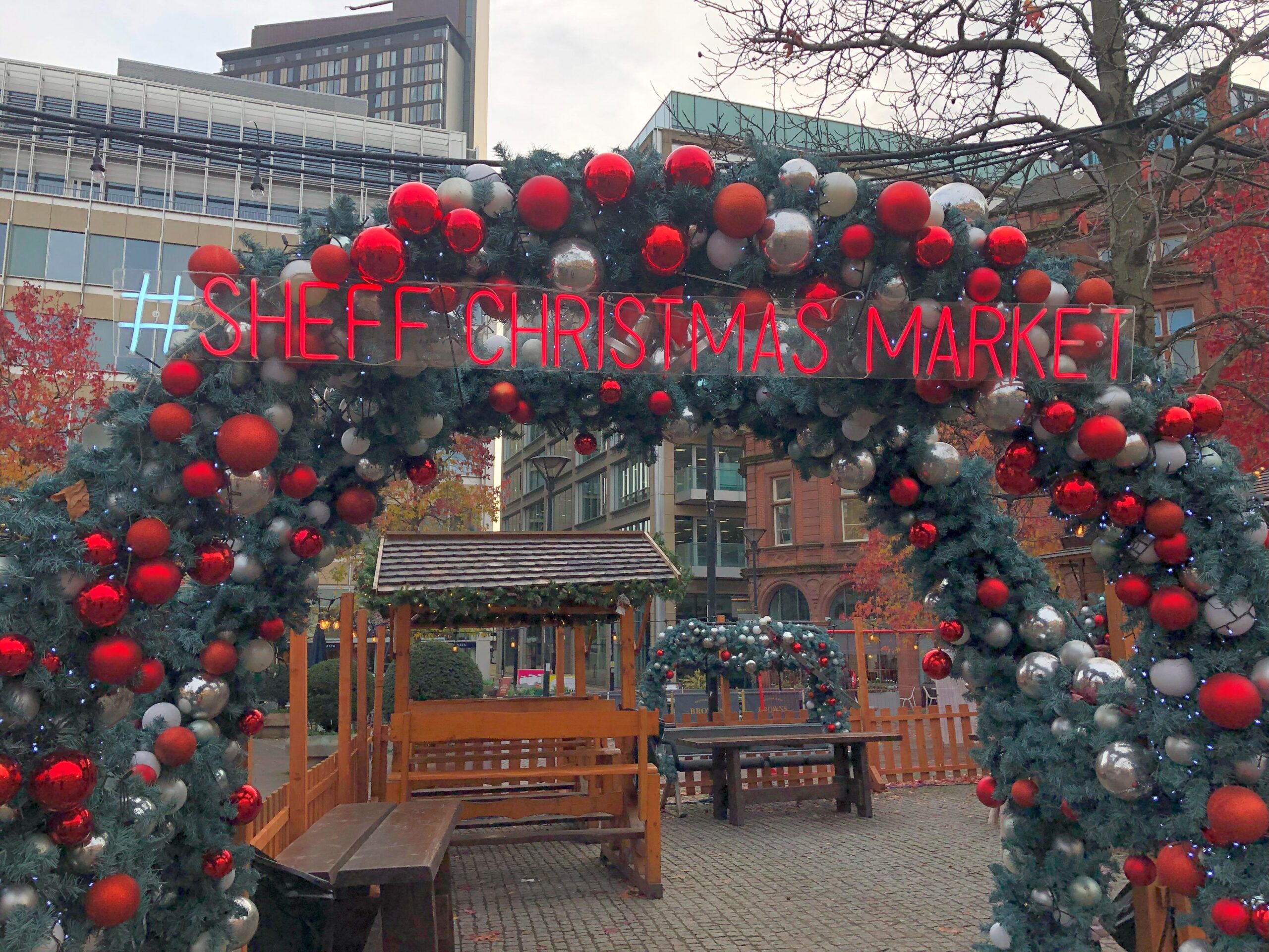 A decorated Christmas arch with the letters 'SHEFFIELD CHRISTMAS MARKET' mounted in red.