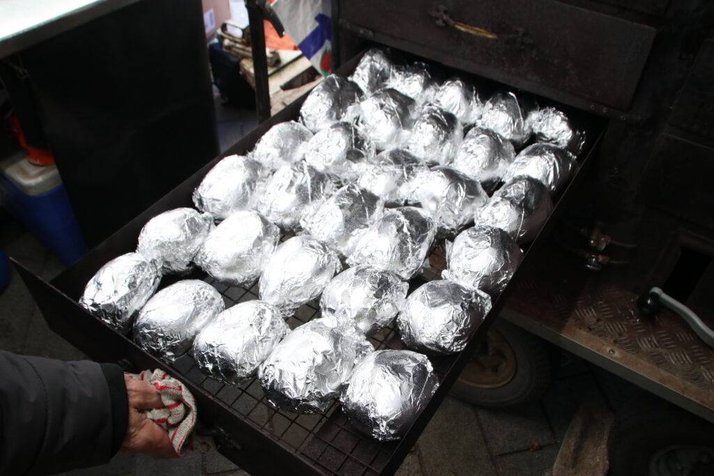 A large oven tray filled with potatoes covered in foil