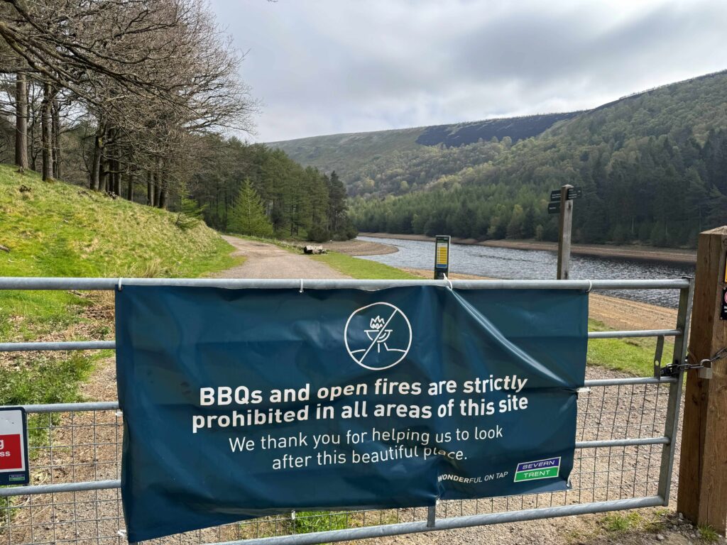 Sign about open fires with burnt hills in background 
